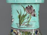 a green vase with a flower on it on a table