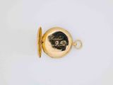 a close up of a gold pocket watch on a white surface
