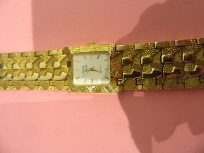 une image montrant un gros plan d'une montre-bracelet posée sur une surface rose