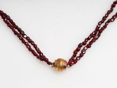 un gros plan d'un collier de perles rouges posé sur une surface blanche