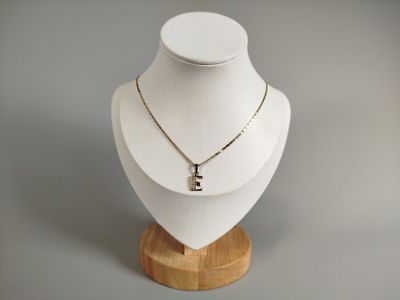 necklace on a mannequin on a wooden stand with a white background