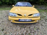 a yellow car that is parked in a gravel lot