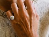 woman wearing a white sweater and a silver bracelet with a diamond ring on her neck