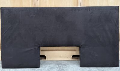 un oreiller noir posé sur une palette en bois