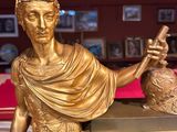 a gold statue of a woman holding a clock in front of a pool table