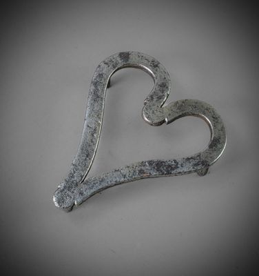 a metal heart shaped object on a white surface