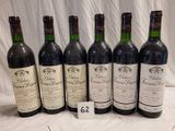 six bottles of red wine are lined up on a table