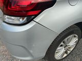 the rear end of a silver car parked on the side of the road