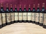 six bottles of wine are lined up on a wooden table
