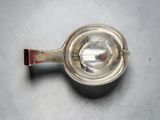 an old silver measuring spoon with a red handle on a white surface