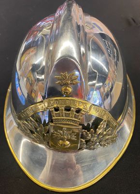 un casque de pompier argenté et doré posé sur une table noire