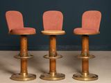 three wooden stools with pink upholstered seats in a room