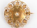 une image d'une broche en or avec une perle au centre
