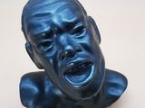 une sculpture bleue représentant le visage d'un homme aux yeux fermés
