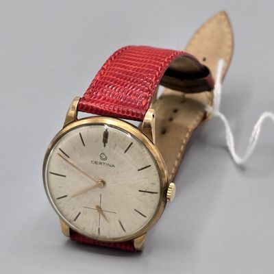 une montre montée sur un bracelet en cuir rouge