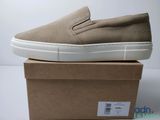 baskets slip-on pour homme, couleur beige, posées sur une boîte en carton