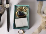a box with a ring, a watch, and a pair of scissors sitting on a table