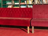 a red couch sitting in front of a bookshelf in a room