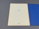 un cahier ouvert, à la couverture bleue, posé sur une table