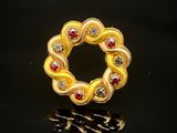 bague-broche jaune et rouge sur fond noir avec reflets
