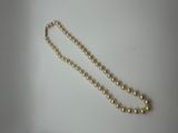 a close up of a pearl necklace on a white surface