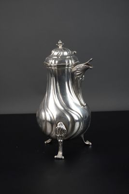 une cafetière en argent posée sur une surface noire