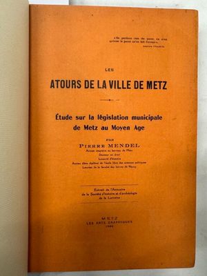 un livre orange posé sur une table près d'un mur blanc