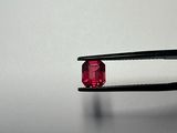 a close up of a pair of pliers holding a red diamond
