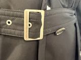 the back of a black jacket with a gold buckle on it