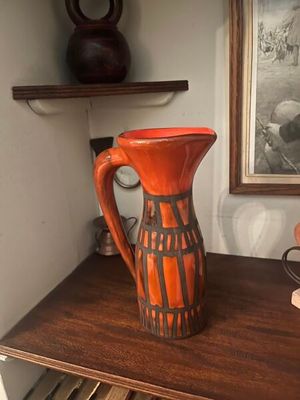 un vase posé sur une table en bois, avec un tableau en arrière-plan