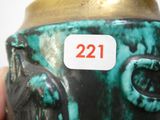 une main tenant un vase vert et noir sur lequel figure le chiffre 21