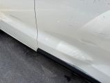 a white car that has been dented and is parked on the side of the road