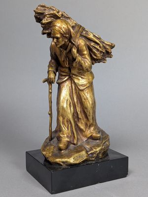une statue en bronze représentant une vieille femme avec une canne, posée sur un socle en marbre