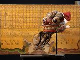 un masque en bois posé sur un socle, avec une carte en arrière-plan