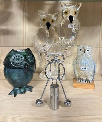 Plusieurs chouettes en verre sont posées sur une étagère à côté d'un bougeoir.
