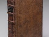 un vieux livre brun posé sur une surface blanche