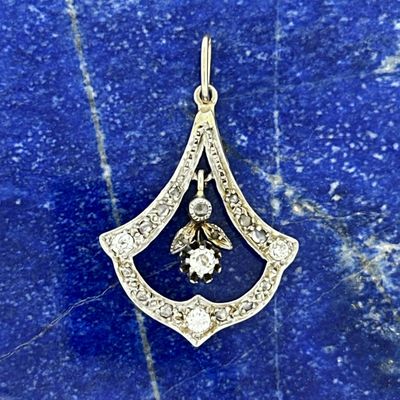 a gold and diamond pendant on a blue marble surface