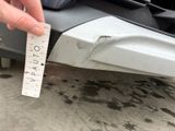 a person holding a measuring tape to measure the front bumper of a car