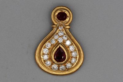 un gros plan sur un pendentif en or orné d'un rubis et d'un diamant en forme de larme