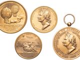 four gold medals of various sizes and shapes on a white background