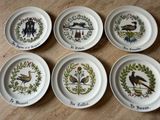 six assiettes ornées de motifs différents, posées sur une table en bois