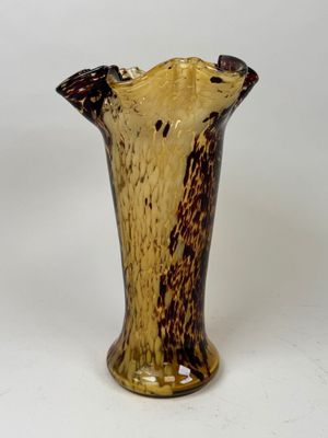 a brown and black vase sitting on a white surface