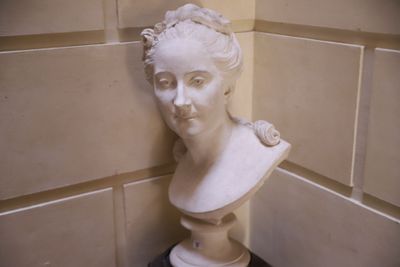 un buste de femme posé sur un socle dans un coin de la pièce