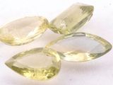 three yellow quartz gems on a white surface