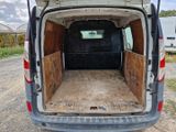 une camionnette blanche dont la porte arrière est ouverte, sur un chemin de terre