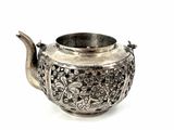 a silver teapot on a white surface with a white background
