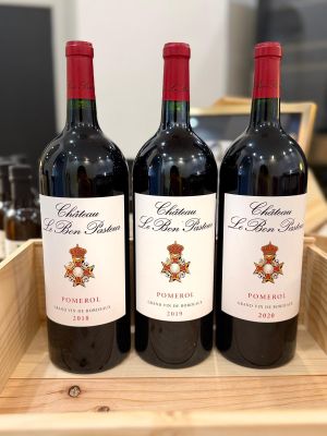 three bottles of red wine sit in a wooden box
