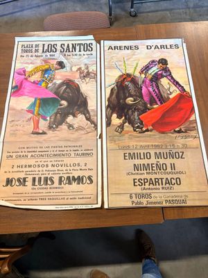 deux affiches posées sur une table, avec une personne debout devant elles