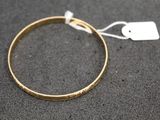 a close up of a gold bracelet with a tag on it
