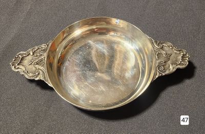 a silver bowl with a handle on a table